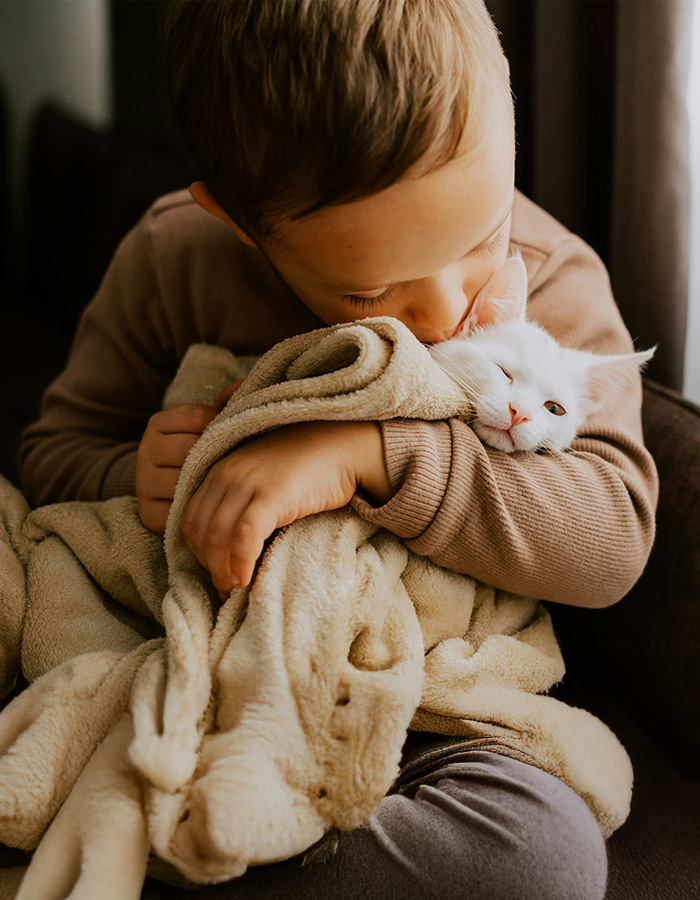 A boy cuddling with his white cat