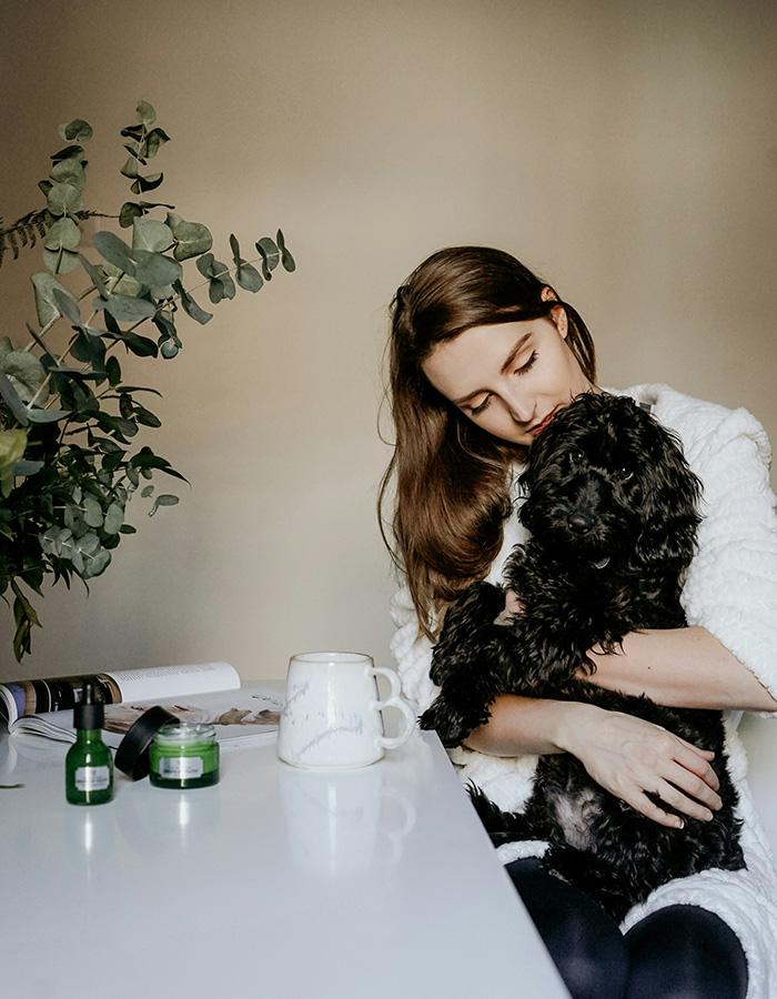 A woman holding her black dog in a nice indoor setting