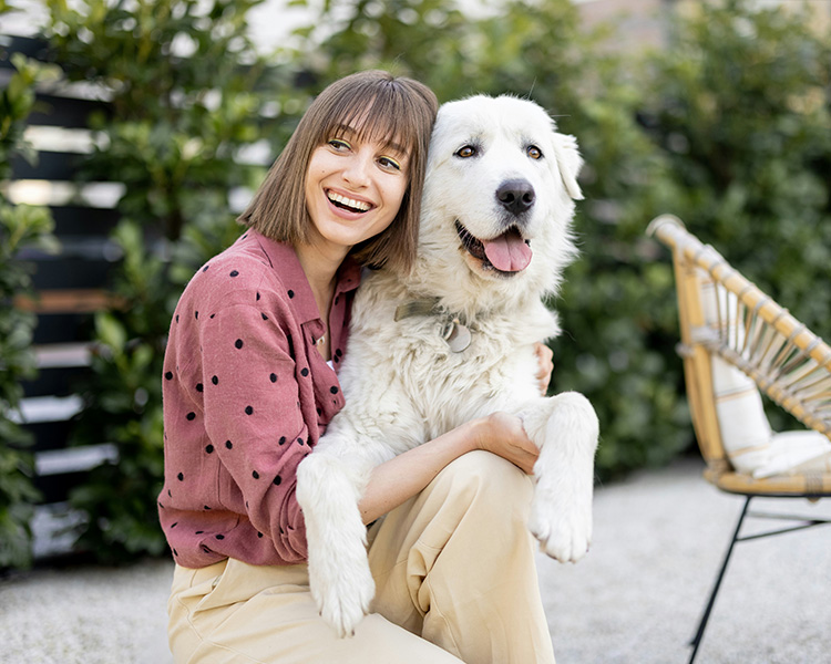 A happy woman kneeling with her large white dog